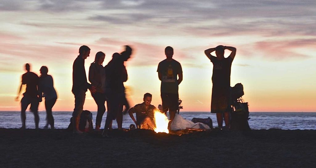 groep mensen bij een strandfeetst rondom een kampvuur