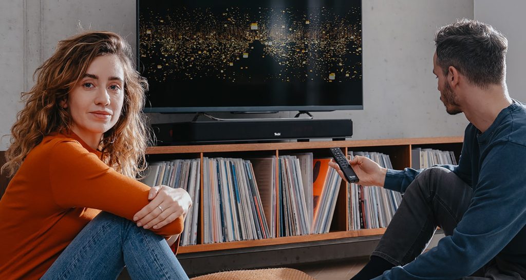 Vrouw en man in de woonkamer voor een sounddeck en tv