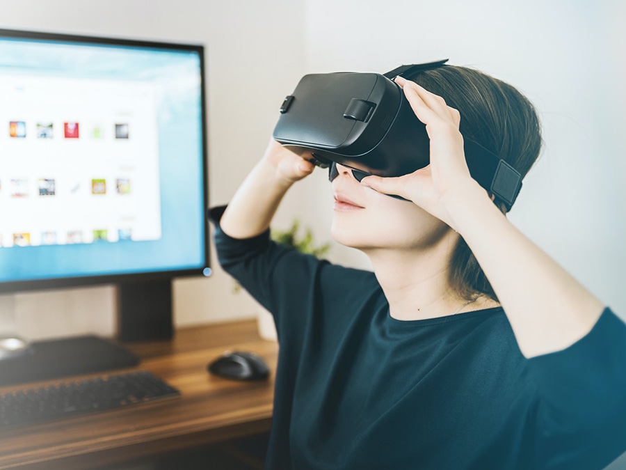 Vrouw met VR bril voor een computer.