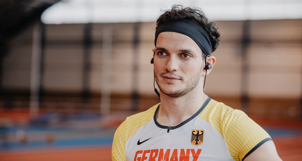 Jonge man in sportkleren met in ear koptelefoon.