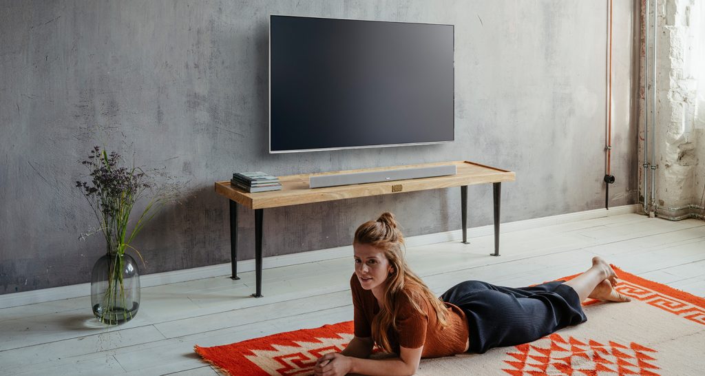 Mujer tumbada en una alfombra frente al televisor. 