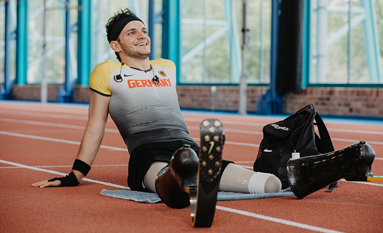 Atleet neemt pauze zittend op een atletiekbaan.