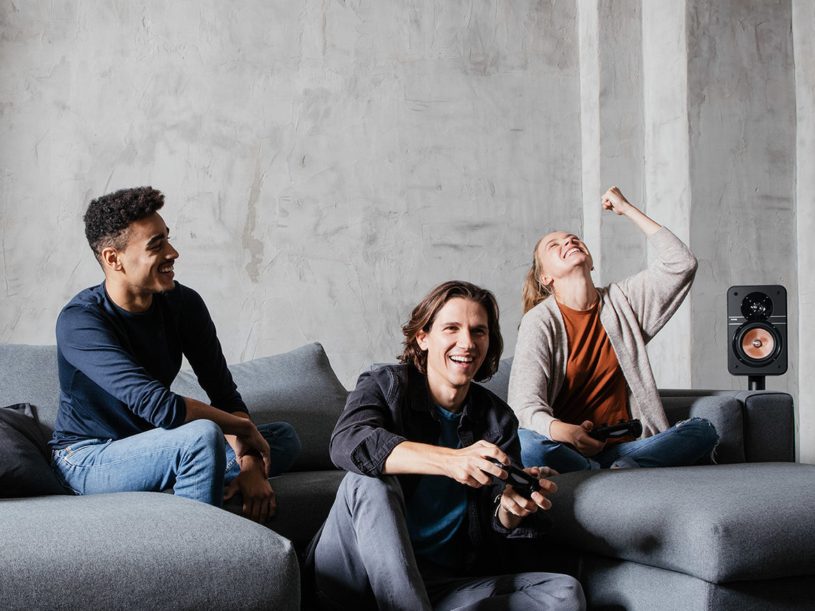 Drie personen die gamen op de bank. 