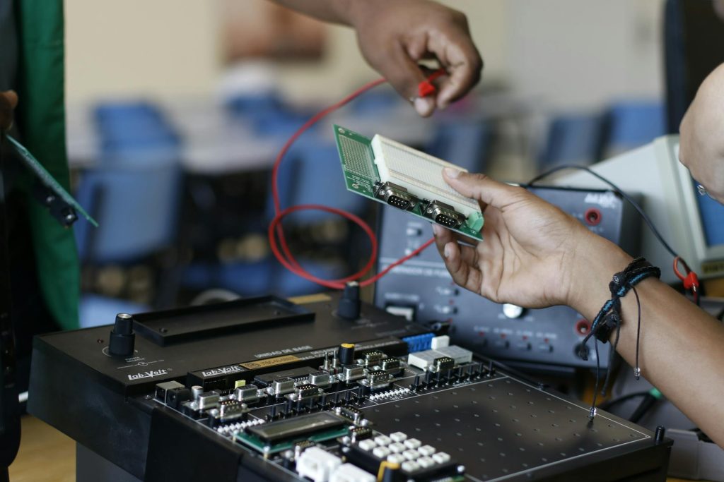 Twee mensen werken aan een elektronische printplaat met kabels