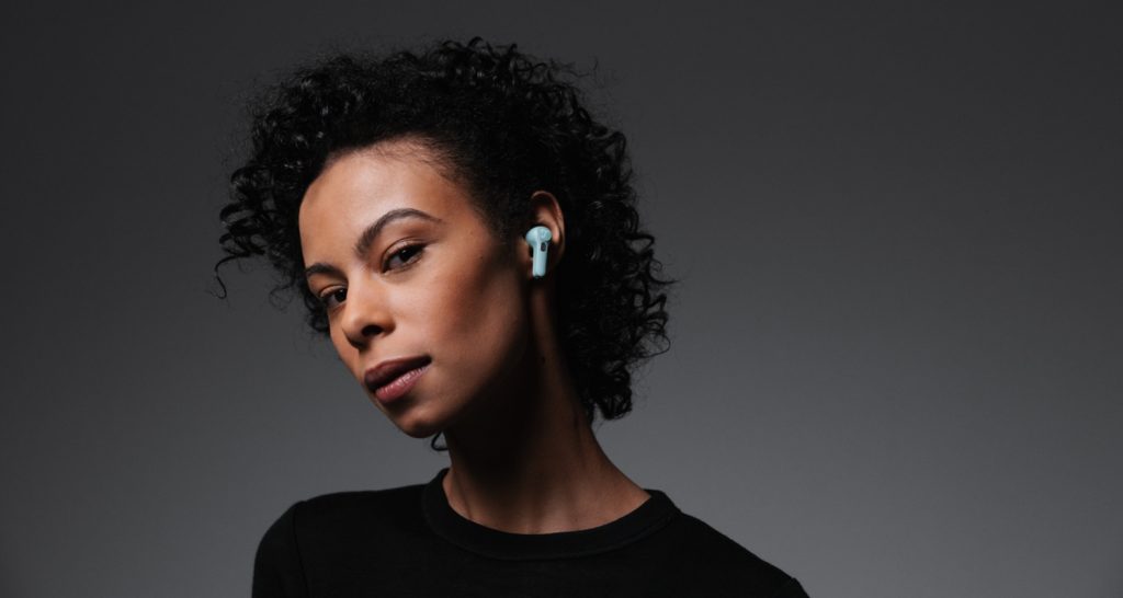 AIRY TWS PRO Portret van een vrouw tegen een zwarte achtergrond, die de Airy TWS PRO oortjes van Teufel in heeft.