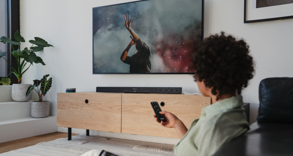 Persoon bedient tv, op het dressoir staat een Cinebar 11