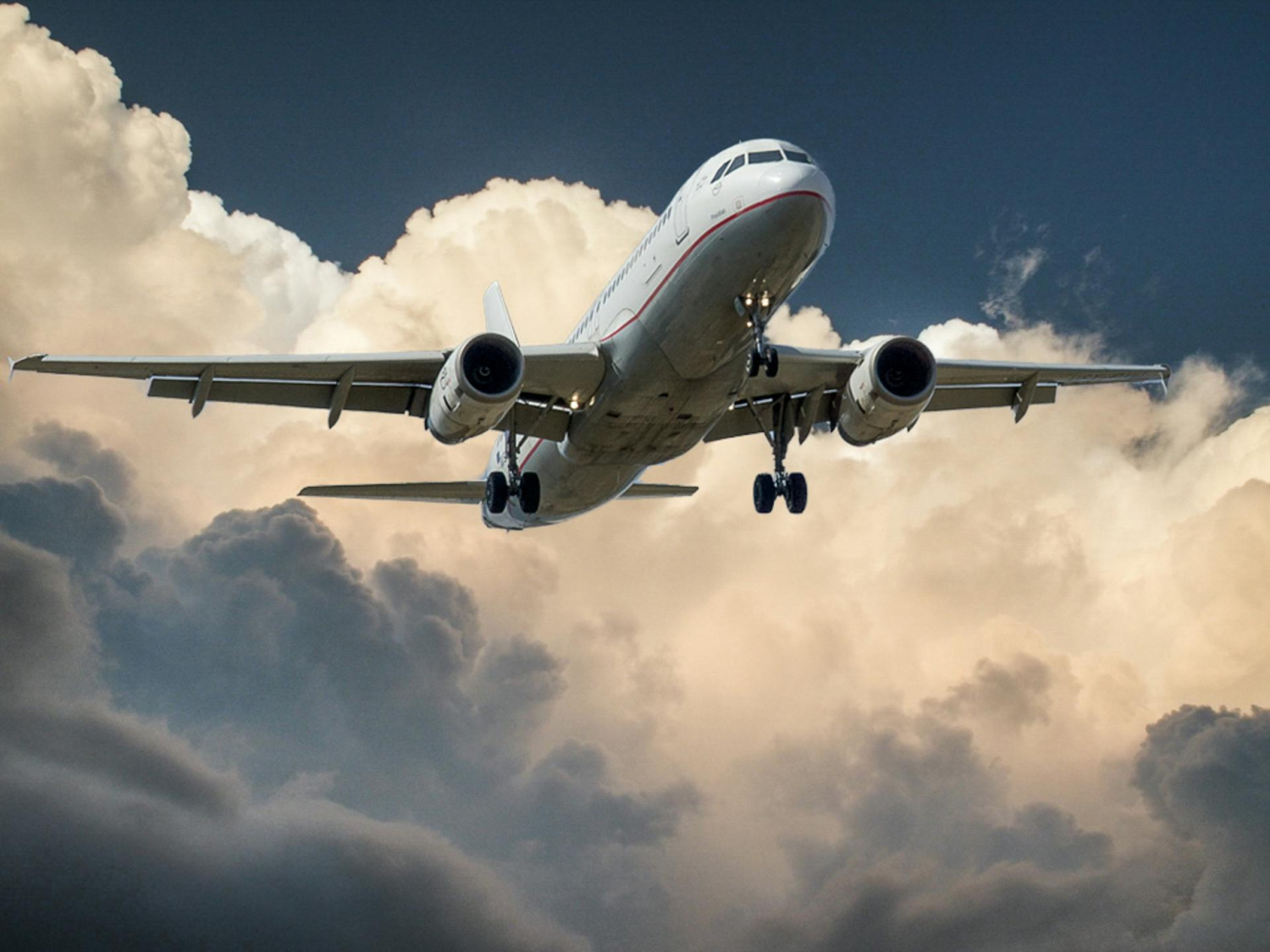 Passagierflugzeug im Landeanflug vor  einer Wolkenkulisse.