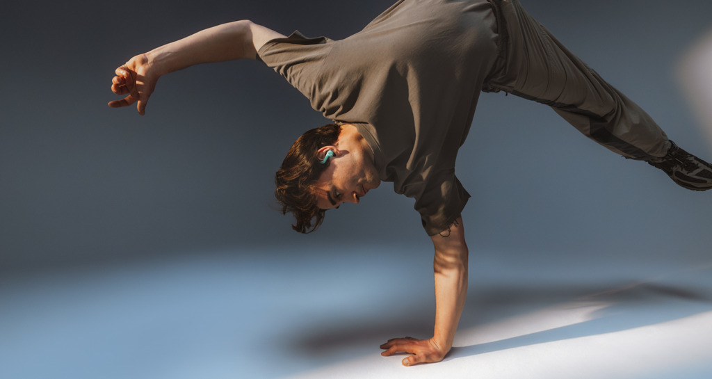 Man doet handstand op 1 hand met oortjes AIRY SPORTS TWS 2 in