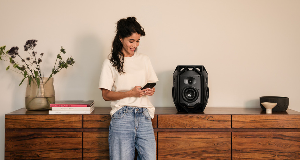 Ikonio op een dressoir met vrouw die muziek uitzoekt op haar telefoon.